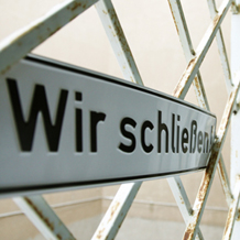 Schild vor Rollgitter WIR SCHLIESSEN