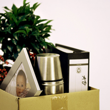 Pappkarton mit Thermosflasche, Schreibtischbild, Büropflanze und Aktenordner