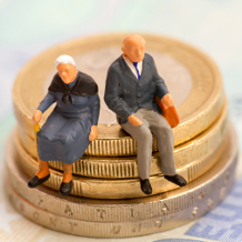 Geringe Rente, älteres Ehepaar sitzt auf Euro-Münzen