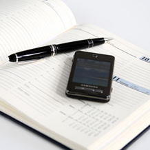 Terminkalender mit Stift und Mobiltelefon