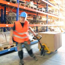 Lagerarbeit zieht ein Hubwagen im Lagerhaus, Lagerist